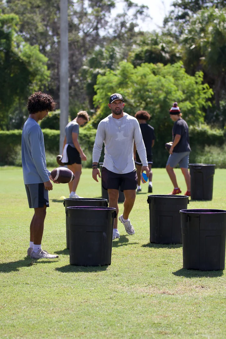 Coach leading quarterbacks through a field session