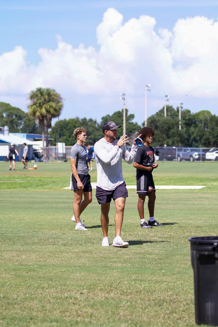 Coach working with quarterbacks on the field