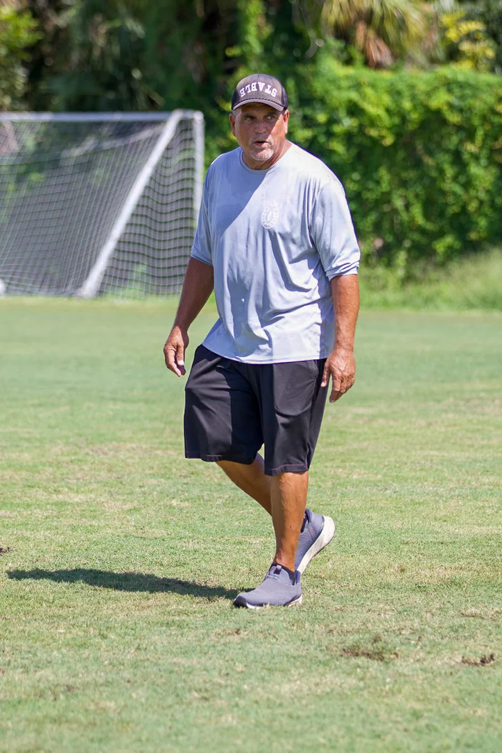 Coach walking across a football field